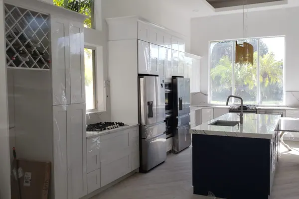 Custom kitchen cabinet install with reclaimed wood accent wall and quartz waterfall island — South Blue Enterprises project in Broward County, FL