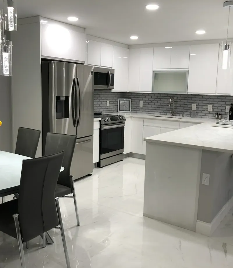 Modern white kitchen with marble countertops, pendant lighting and dining area — South Blue Enterprises kitchen install Deerfield Beach FL