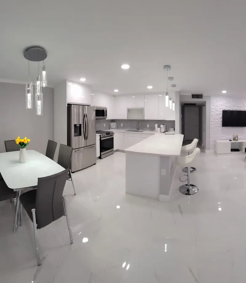 Open-concept kitchen and living room with white cabinetry, marble flooring and pendant lighting — South Blue Enterprises full home interior in Broward County, FL