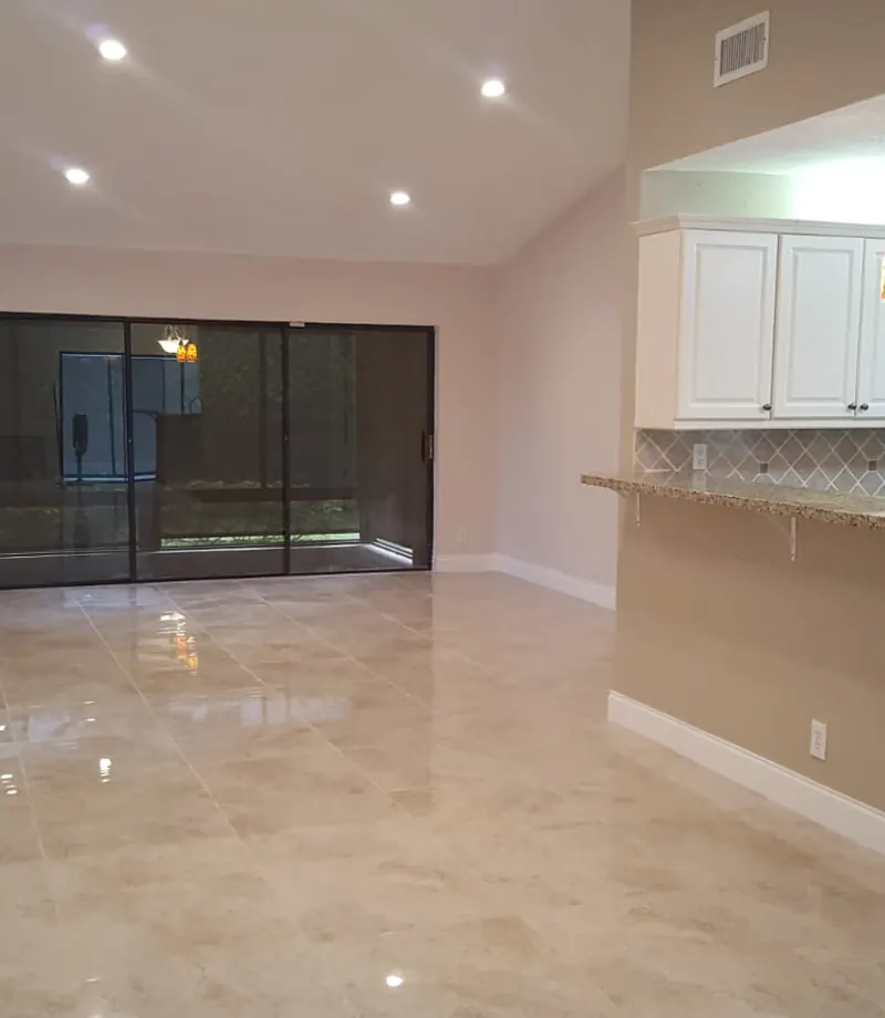 Open kitchen with granite breakfast bar, white shaker cabinetry and travertine flooring — South Blue Enterprises kitchen and tile install in South Florida