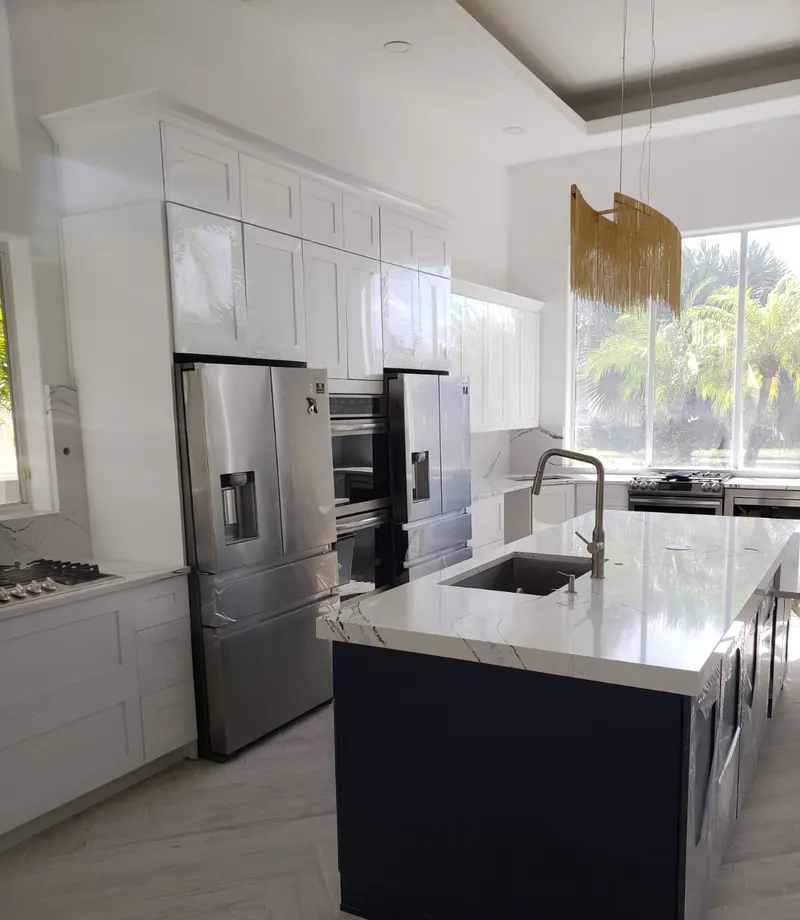 Luxury kitchen with calacatta marble island, navy cabinetry and tropical Florida view — South Blue Enterprises kitchen install Boca Raton FL