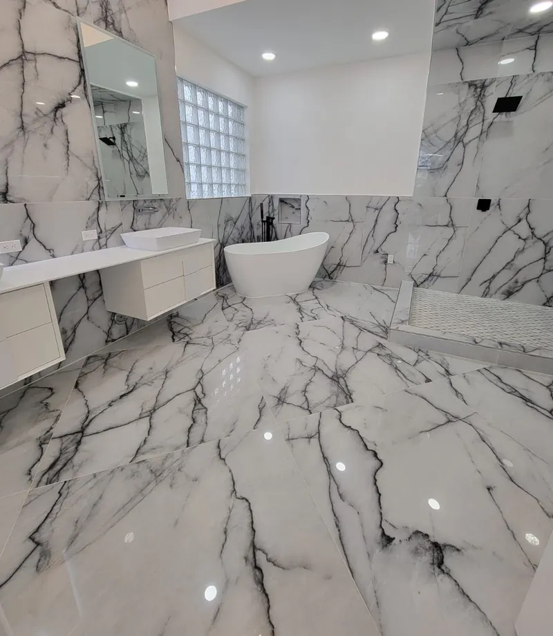 Luxury bathroom with veined marble walls and floor, freestanding soaking tub and frameless glass shower — South Blue Enterprises bathroom install in Broward County, FL