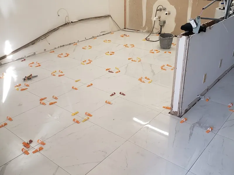 Large format marble-look porcelain tile installation in progress with leveling clips — tile installation by South Blue Enterprises in Broward County, FL